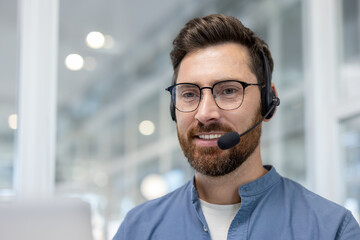 A man with a headset and glasses smiles, likely assisting customers, set against a bright, blurred...