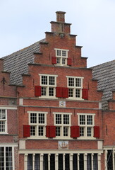 Binnenhaven Brick House Facade with Stepped Gable and Red Wooden Shutters in Hoorn, Netherlands