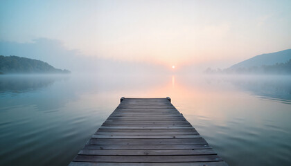 Fototapeta premium Serene wooden dock extending over misty lake at sunrise 
