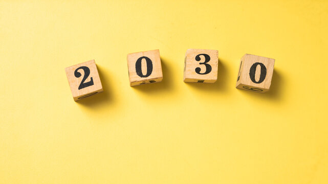 Wooden blocks with black numbers forming "2028" arranged in a row on a solid bright yellow background. Symbolizing future year, new beginnings, or goal setting