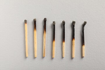 Burnt matches on grey background, flat lay