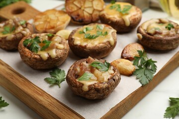 Delicious stuffed mushrooms with melted cheese, garlic and parsley on white table, closeup
