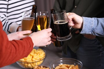 Friends clinking glasses of beer at table, closeup