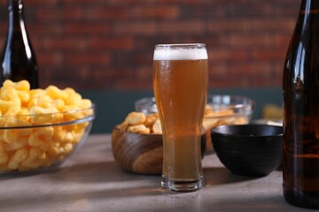 Beer and snacks on grey table indoors, closeup