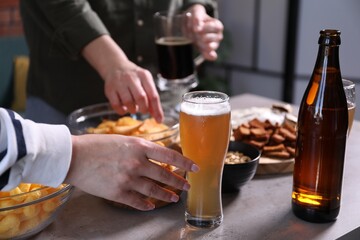 Friends with beer and snacks at grey table, closeup