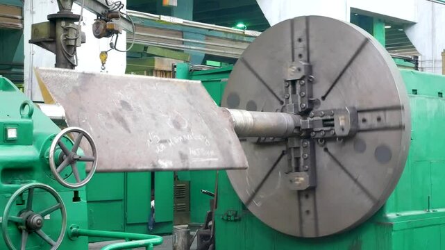 A large metal part rotates on a milling machine in the workshop of a large industrial enterprise. Production processes at a heavy industry enterprise.