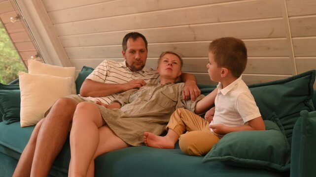 mother, father and son reading a book in the living room, reading together with a child. Parents teaching preschoolers to read. Mum and dad tell stories