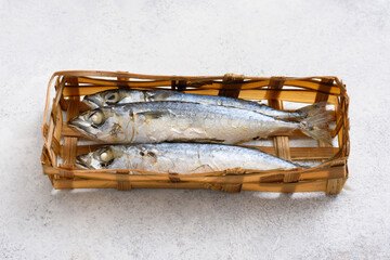 Ikan pindang in bamboo basket, Indonesian traditional fresh salted fish on white table