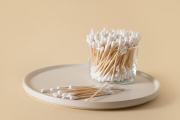 Wooden ecological cotton swab in glass jar on beige background. Zero waste, sustainable resources. Eco friendly natural personal bath care accessory.
