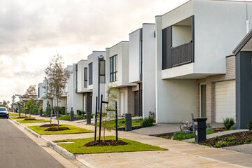 A quiet residential street lined with modern double-storey townhouses in a newly developed outer...