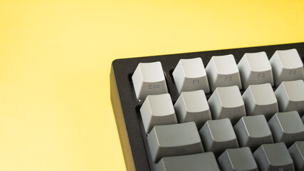 Minimalist mechanical keyboard with gradient gray keycaps placed on a vibrant yellow background,...
