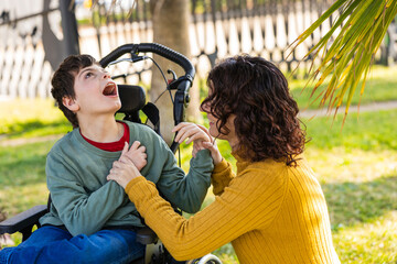 Mother playing with son with disability in wheelchair outdoors