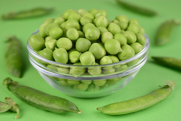 Young green peas in a bowl on a green background. Close-up.
