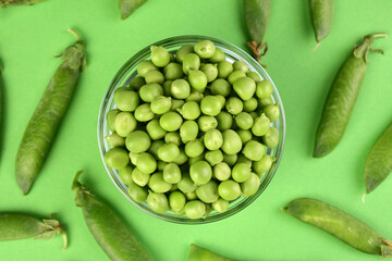 Young green peas in a bowl on a green background. Flat lay.
