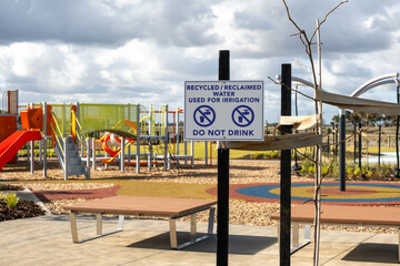 A recycled water warning sign displayed at a suburban playground, cautioning the public not to...