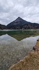 Calm mountain lake with mirrored peaks under overcast skies