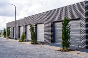 Row of contemporary brick garages with roller doors of townhouses in a new suburban housing estate. Concept of urban planning in an outer residential suburb of Australia.