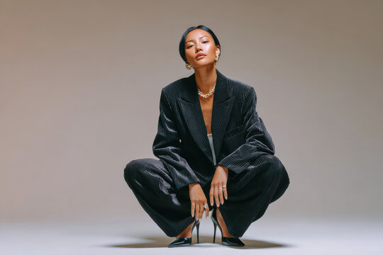 Young businesswoman wearing corduroy suit squatting in studio