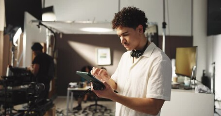 Typing, producer and man with tablet for editing software, photoshoot and production in studio. Schedule, creative director and person with digital tech for magazine catalogue, photography or film