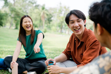 Diverse young adults sharing a fun conversation outdoors on a break. Multicultural youth friends smiling and relaxing in nature