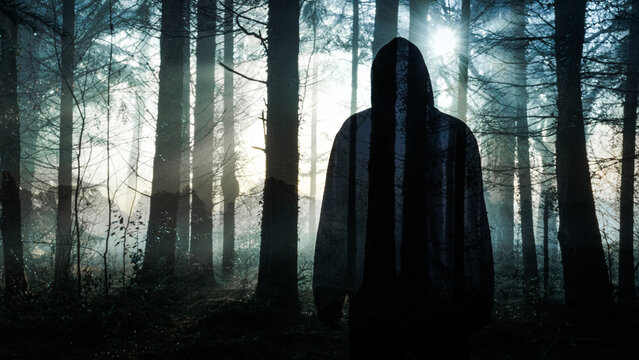 A double exposure of a hooded horror figure, standing in a spooky forest on a foggy winters day