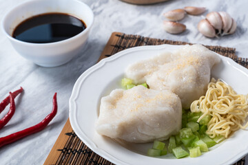 Traditional Indonesian pempek served with diced cucumber, yellow noodles, and spicy vinegar sauce on the side. A savory delicacy made from fish and tapioca