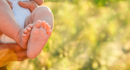 little baby feet outdoors against sunny weather and summer grass