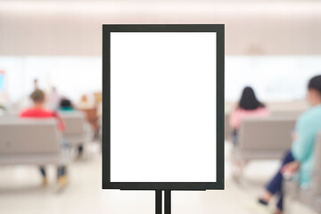 Blank vertical signage board mockup in hospital waiting area with blurred patients sitting in background scene