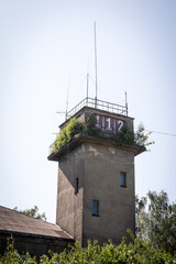 Abandoned Concrete Tower with Emergency Number 112 and Overgrown Vegetation on Rooftop