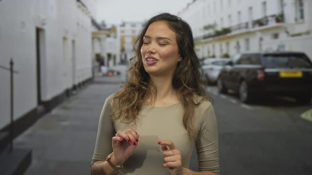 Woman pinches nose on narrow cobblestone street with parked cars and white buildings; stink disgust.