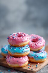 A pile of pink and blue glazed donuts on a wooden table.
