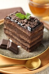 Piece of delicious chocolate cake with mint and tea on table, closeup