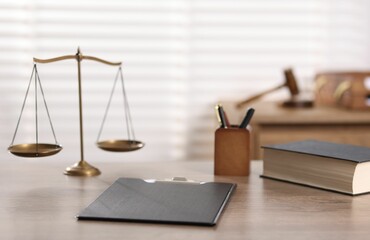 Judge. Scales, book, clipboard and pens on wooden table in office, selective focus