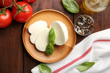 Tasty mozzarella, tomatoes and basil on wooden table, flat lay