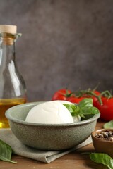 Tasty mozzarella balls, tomatoes, oil and basil on wooden table, closeup