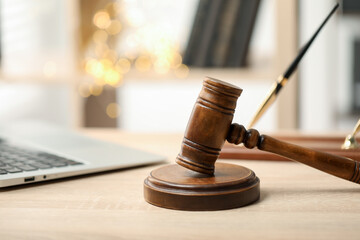 Judge's gavel on wooden table in office, closeup. Bokeh effect
