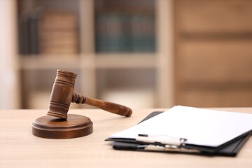Judge's gavel and clipboards on wooden table in office, closeup
