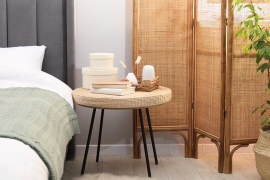 Side table with books and decor near bed indoors