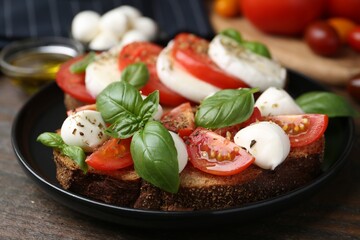 Tasty sandwiches with mozzarella cheese, tomatoes, basil and spices on wooden table, closeup