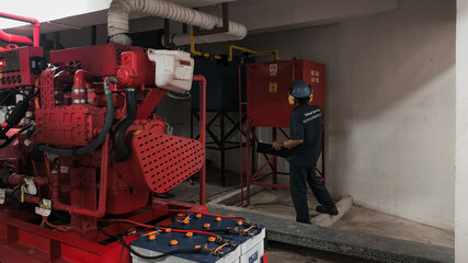 Technician inspecting a red industrial generator and control panel in a utility room.