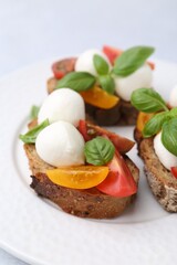 Tasty sandwiches with mozzarella cheese, tomatoes and basil on white table, closeup