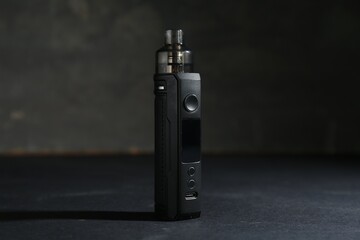 One electronic smoking device on dark table against grey background, closeup