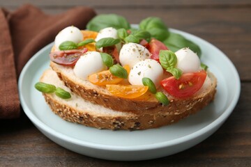 Tasty sandwich with mozzarella cheese, tomatoes and basil on wooden table, closeup
