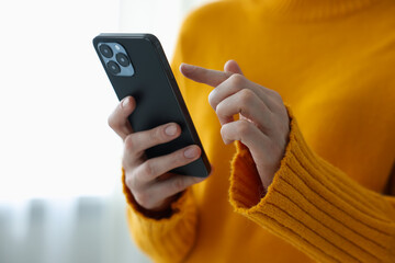 Woman using modern smartphone at home, closeup