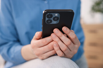 Woman using modern smartphone at home, closeup