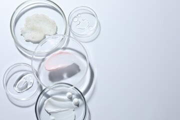 Different cosmetic products in Petri dishes on white background, flat lay. Space for text