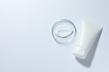 Cosmetic product in Petri dish and tube on white background, top view. Space for text © New Africa