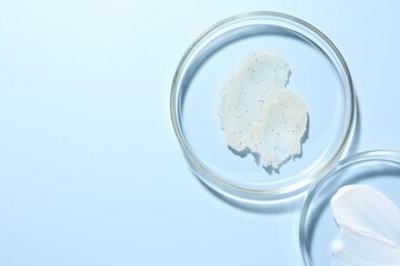 Different cosmetic products in Petri dishes on light blue background, flat lay. Space for text