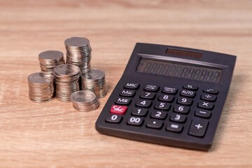 Finance, business, budget or investment concept. Stack of coins and calculator on wooden table.