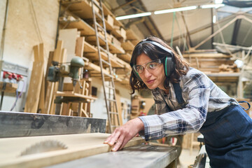 Skilled worker focuses on wood cutting in a busy lumberyard